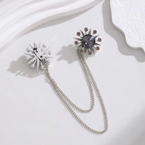 Vintage silver sunburst chain brooch with grey gemstone and rhinestones on white display