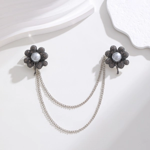 Macro shot of vintage silver flower brooch with grey pearls and layered metal fringe chains