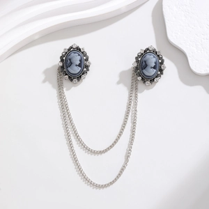 Macro detail of vintage brooch with dual chains and crystal-embellished portrait relief