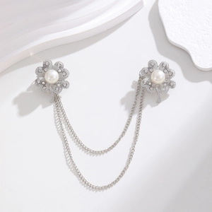Detail of silver clover brooch with white pearls, rhinestones and double chain link