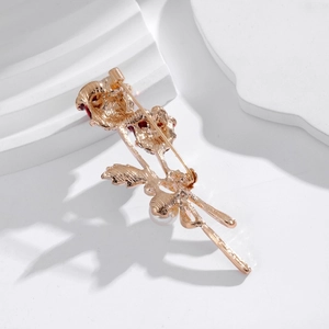 Detailed back view showing the safety pin clasp on a golden rose brooch with red flower