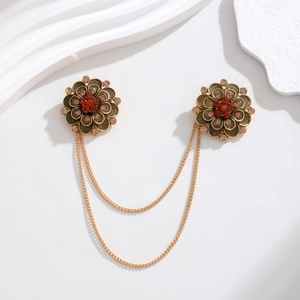 Macro detail of vintage floral brooches with bronze chains and red rhinestones