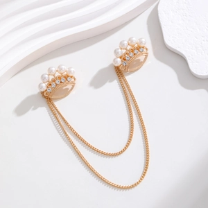 Détail de broches doubles couronnes dorées avec perles, strass et doubles chaînes