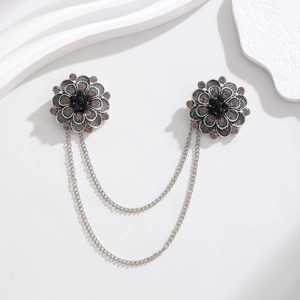 Macro detail of retro silver flower brooches with black gems and double hanging chains