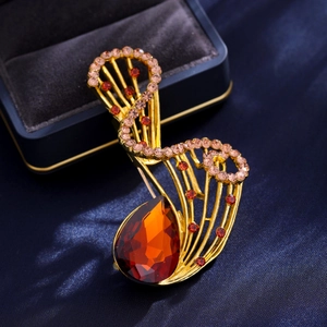Dettaglio della spilla vintage ad ala con cristallo arancione su sfondo di raso blu