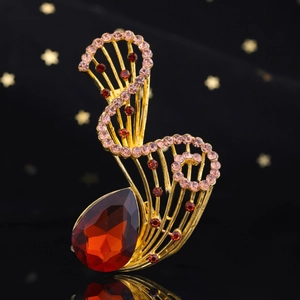 Dettaglio di spilla vintage dorata con cristallo rosso e strass rosa su base nera