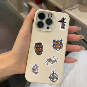 Beige iPhone case featuring artistic stickers of a witch, tiger, and castle in hand