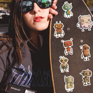Retro whimsical robot stickers applied to a skateboard held by a female model in warm sunlight