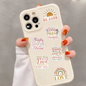 Close-up of BOHO art stickers with positive quotes on a beige phone case surface