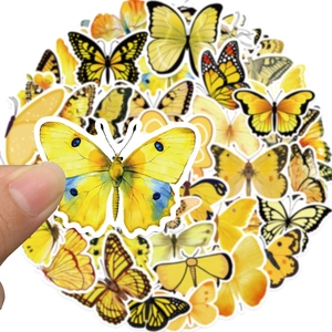 Detail view of yellow butterfly decorative stickers set for journals with hand for scale