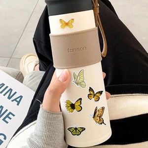 Detailed view of stainless steel thermos with butterfly stickers and brown leather sleeve