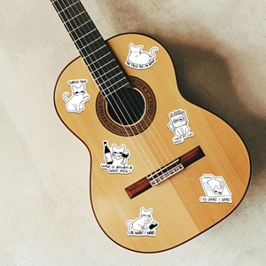 Detail of funny hand-drawn cat meme stickers applied on a wooden guitar surface