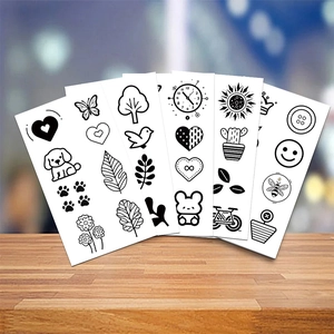 Detailed close-up of various cute minimalist cartoon temporary tattoo stickers on wood