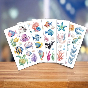 Detail view of five sheets of watercolor sea animal tattoo stickers on a wood table