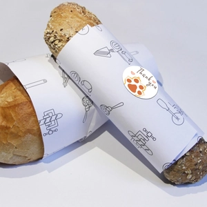 Close-up of cute cat paw Thank You sticker sealing a minimalist white paper bread wrap
