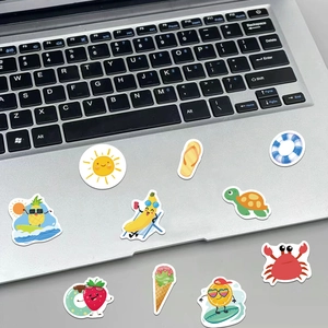 Detail showing waterproof cartoon beach stickers on a laptop with vibrant summer designs