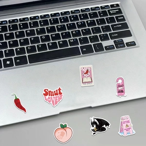 Close-up of creative bookish stickers on a laptop featuring dragon and tarot designs