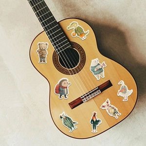 Détail d'autocollants d'animaux en dessin animé posés sur le corps d'une guitare en bois