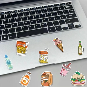 Close-up of waterproof cartoon snack stickers applied on a silver laptop surface