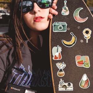 Close-up of artistic BOHO style stickers with retro camera and guitar designs on a skateboard