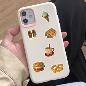 Close-up of a cream iPhone case with food stickers and pink camera lens protector