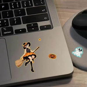 Close-up of Halloween theme stickers with witch and pumpkin on a gray laptop surface