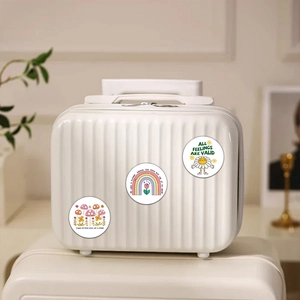 Close-up of waterproof mental health stickers with floral designs on a white suitcase