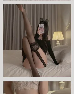 Detail of elegant black lace garter belt set and sheer thigh high stockings on bed