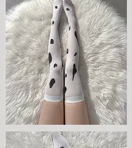 Détail de chaussettes hautes à motif vache avec bords côte sur fond en peluche blanc