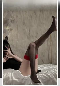 Close-up of black sheer thigh-high stockings featuring a bold red elastic wide band