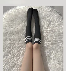 Close-up of black thigh high stockings with white triple stripes on plush white rug