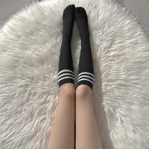 Japanese style black knee high socks with three white stripes on white faux fur carpet