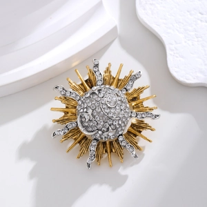 Detailed macro view of vintage sunburst brooch featuring silver and gold plating with rhinestones
