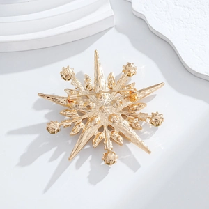 Close-up of golden starburst brooch back with metallic texture and safety pin clasp