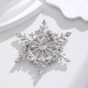 Macro view of silver snowflake brooch back showing the sturdy pin clasp and blue rhinestones