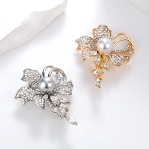 Close-up of elegant flower brooches with inlaid rhinestones, pearls and crystal drops