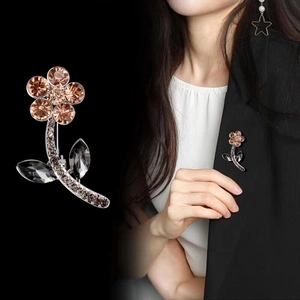 Elegant floral brooch with champagne rhinestones on a black suit lapel view