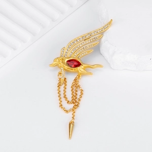 Macro detail of golden phoenix brooch with red stone, wings and chain tassels