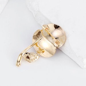Back view of gold apple poppy brooch with textured leaves and pin on white stone