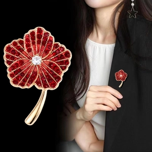 Elegant poppy flower brooch with red crystals and gold-plated stem on a black suit lapel