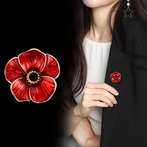 Broche fleur de pavot en émail rouge avec dorure et cristal noir sur un costume noir