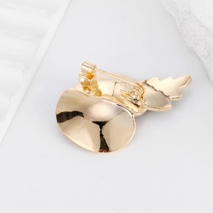 Back view of gold-plated poppy flower brooch with metal pin clasp on white stone
