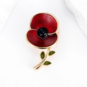Close-up of red poppy brooch with detailed enamel petals and sparkling gold stem