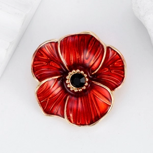 Détail de la broche coquelicot en émail rouge avec bords dorés et pierre noire facettée