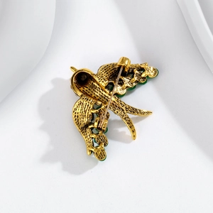 Exquisite gold swift bird brooch with emerald green stones and detailed feather texture