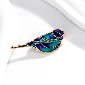 Detail van de emaille vogelbroche met gouden randen en levendige blauwgroene druppelolie