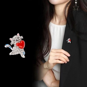 Broche chat scintillante avec cœur et strass sur base argentée, portée sur costume noir