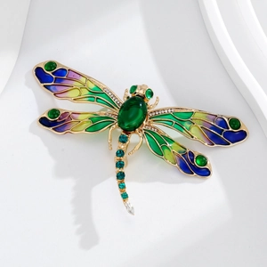 Macro d'une broche libellule avec ailes en émail dégradé et pierre précieuse verte