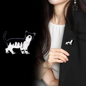 Jolie broche chat en émail noir et blanc épinglée sur le revers d'une veste