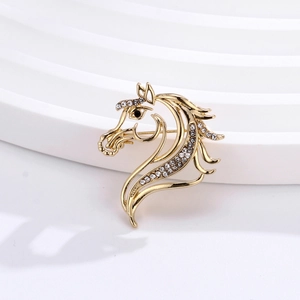 Close-up of golden horse head brooch with white rhinestones and black gem on white steps